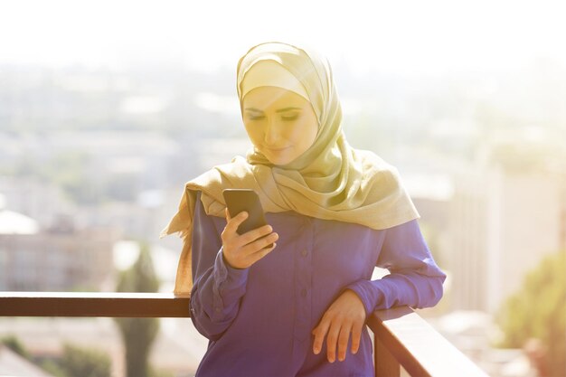 Porträt einer glücklichen asiatischen Frau, die Hijab trägt und mit dem Handy anruft