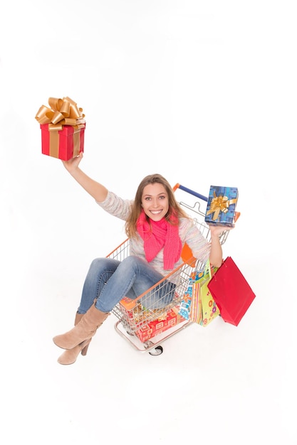Porträt einer glücklichen Dame, die mit vielen Geschenken im Einkaufswagen liegt. Draufsicht einer zahnigen lächelnden Frau, die Weihnachtsgeschenke hält.