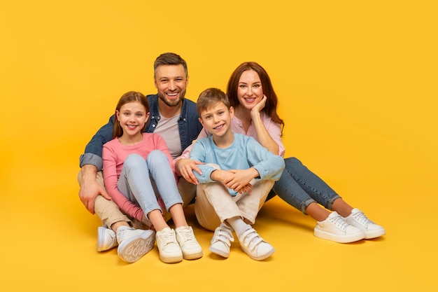Porträt einer glücklichen Familie, die auf Gelb sitzt