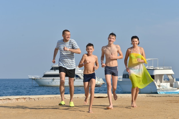 Porträt einer glücklichen Familie, die im Sommer am Strand läuft