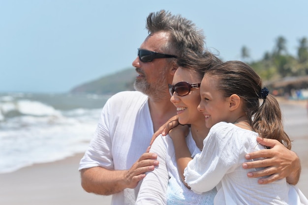 Porträt einer glücklichen Familie, die sich am Sandstrand umarmt und auf das Meer blickt