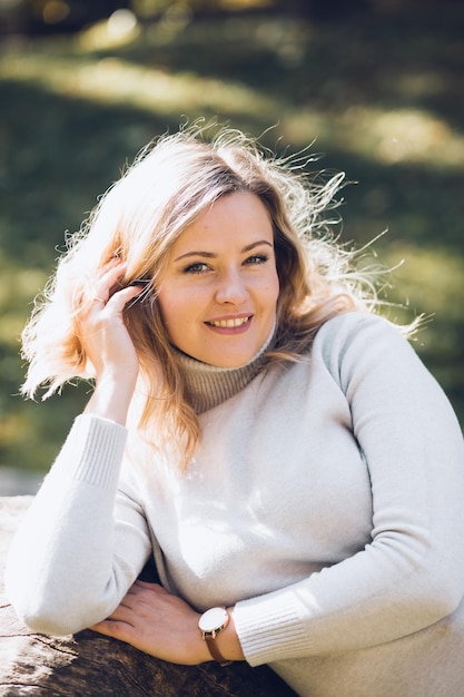 Foto porträt einer glücklichen frau, die an einem sonnigen tag im herbststadtpark sitzt, nahaufnahme einer erwachsenen dame in legerer kleidung