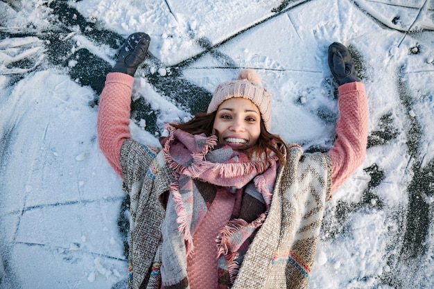 Porträt einer glücklichen Frau, die auf der gefrorenen Seeoberfläche liegt