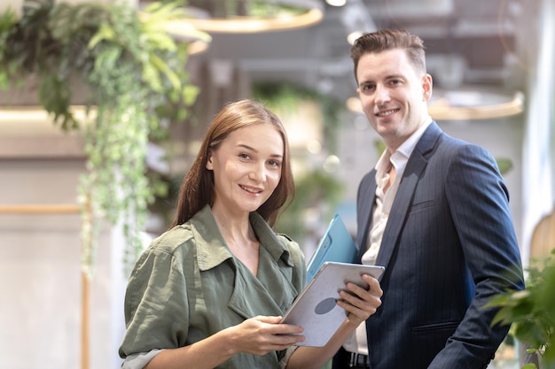 Porträt einer glücklichen Frau, die ein Tablet-Gerät hält und mit Kollegen im Hintergrund an der Theke des Café-Cafés sitzt Concept Business Coffee Time mit intelligenter Technologie funktioniert