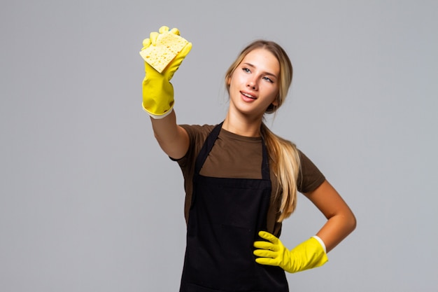 Porträt einer glücklichen Frau, die Hausaufgaben trägt, Gummihandschuhe trägt und Reinigungsmittel mit Schwamm hält und gute Laune hat. Junges Dienstmädchen, das fröhlichen Blick hat, bevor es das Haus putzt. Hygiene, Reinigungskonzept