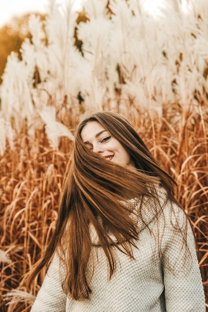 Porträt einer glücklichen Frau, die ihr Haar wellenartig bewegt.