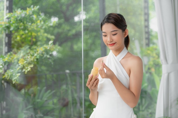 Porträt einer glücklichen Frau, die zu Hause eine gelbe Vitaminpille hält