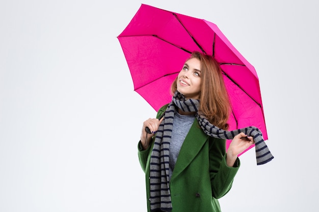 Porträt einer glücklichen Frau mit rosa Regenschirm isoliert auf weißem Hintergrund und nach oben schauend