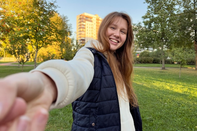 Porträt einer glücklichen, fröhlichen jungen schönen Frau, die im Sommer oder im goldenen Herbstpark draußen spaziert