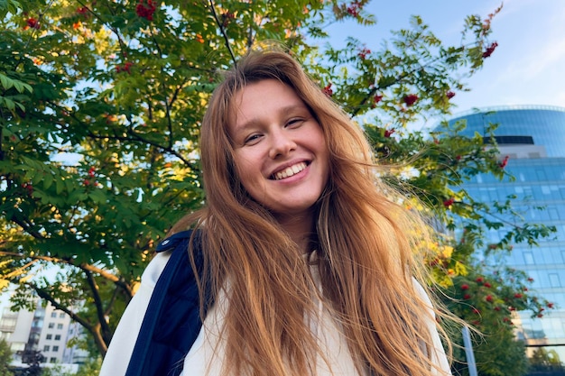 Porträt einer glücklichen, fröhlichen jungen schönen Frau, die im Sommer oder im goldenen Herbstpark draußen spaziert