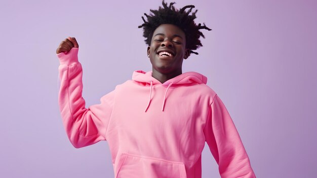 Porträt einer glücklichen jungen afroamerikanischen Frau mit Afro-Frisur, die einen rosa Kapuzenpullover auf lilafarbenem Hintergrund trägt