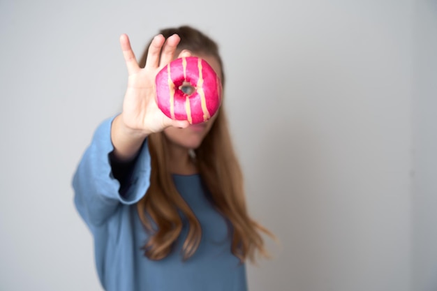 Porträt einer glücklichen jungen blonden Frau, die mehrfarbige Donuts zeigt