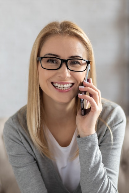 Porträt einer glücklichen jungen Frau, die am Telefon spricht