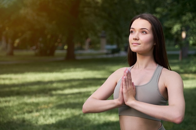 Porträt einer glücklichen jungen Frau, die an einem Sommertag im Park Yoga praktiziert