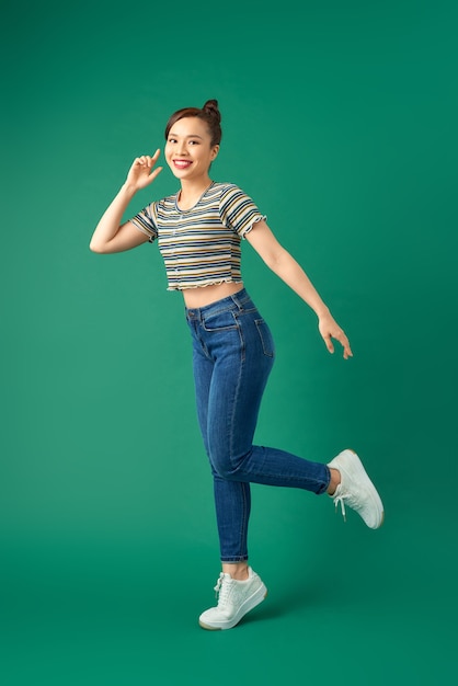 Porträt einer glücklichen jungen Frau, die auf Grün tanzt