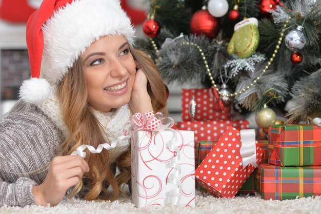 Porträt einer glücklichen jungen Frau in Weihnachtsmütze mit Weihnachtsgeschenk