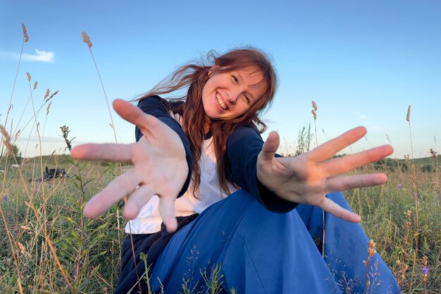 Porträt einer glücklichen jungen Frau oder eines Teenagers, die sich an einem sonnigen Sommertag auf dem Feld auf dem Land amüsiert