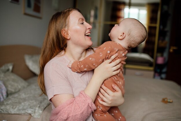 Porträt einer glücklichen jungen Mutter mit Baby in den Armen Das Konzept einer glücklichen Familie