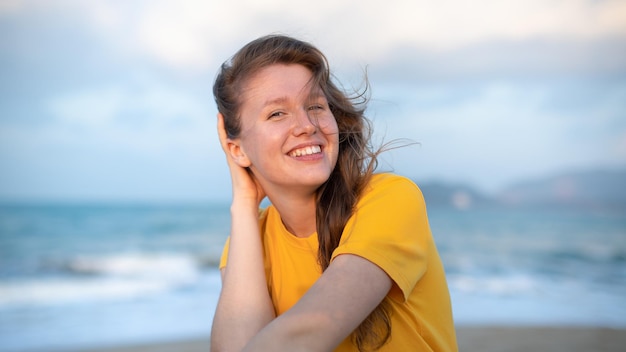 Porträt einer glücklichen jungen, unbeschwerten Frau, die den Sommerurlaub am Meer genießt und im Strandsand spaziert