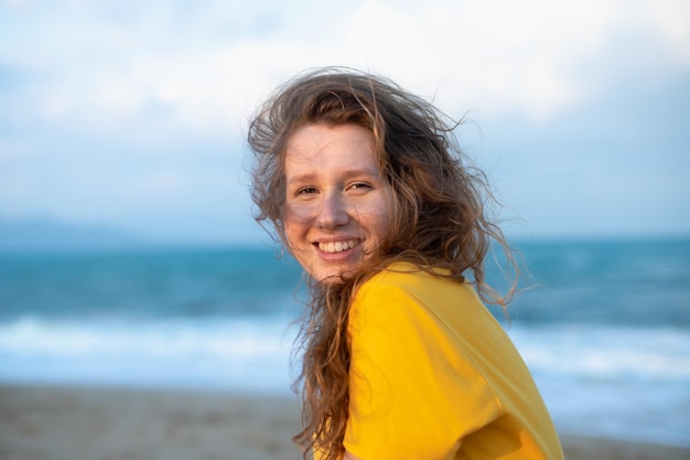 Porträt einer glücklichen jungen, unbeschwerten Frau, die den Sommerurlaub am Meer genießt und im Strandsand spaziert