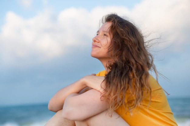 Porträt einer glücklichen jungen, unbeschwerten Frau, die den Sommerurlaub am Meer genießt und im Strandsand spaziert