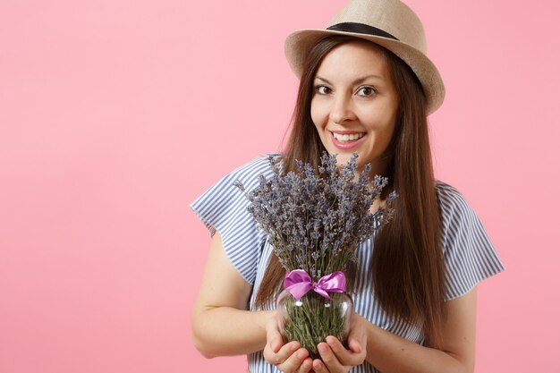 Porträt einer glücklichen jungen, zarten frau in blauem strohhut, die einen strauß schöner lila lavendelblüten hält, einzeln auf hellem rosafarbenem hintergrund. urlaubskonzept zum internationalen frauentag