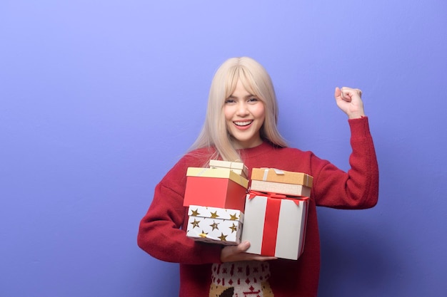 Porträt einer glücklichen kaukasischen jungen Frau mit Geschenkbox auf violettem Hintergrund