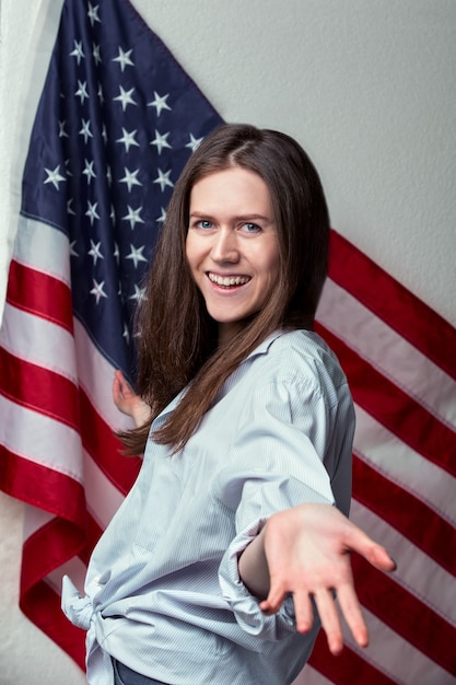 Porträt einer glücklichen lachenden schönen jungen Frau auf einer Oberfläche der amerikanischen Flagge