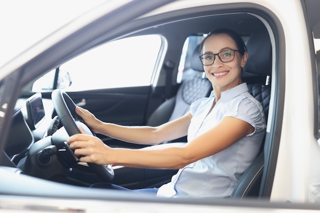 Porträt einer glücklichen lächelnden Frau, die ein neues Auto-Testfahrtkonzept fährt