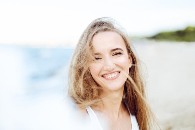 Porträt einer glücklichen lächelnden Frau in freier Glückseligkeit am Meerstrand, die während des Reisens, der Ferien, des Urlaubs im Freien die Natur genießt.