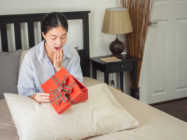 Porträt einer glücklichen lächelnden Frau öffnen eine Geschenkbox auf Bett