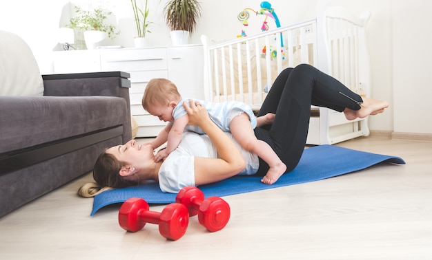 Porträt einer glücklichen Mutter, die zu Hause Sport macht und Spaß mit ihrem Baby hat