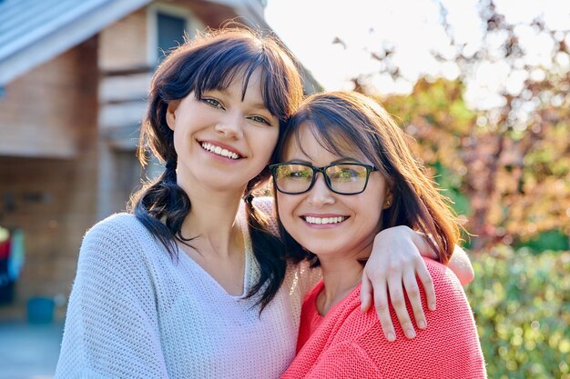 Porträt einer glücklichen Mutter und ihrer Tochter im Teenageralter, die in die Kamera schauen