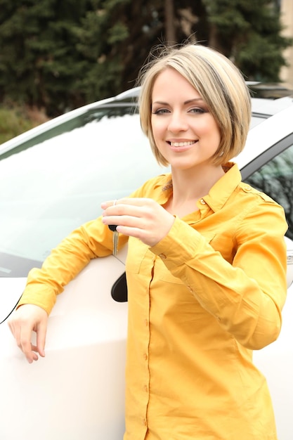 Porträt einer glücklichen schönen Frau mit Autoschlüsseln, die in der Nähe des Autos stehen