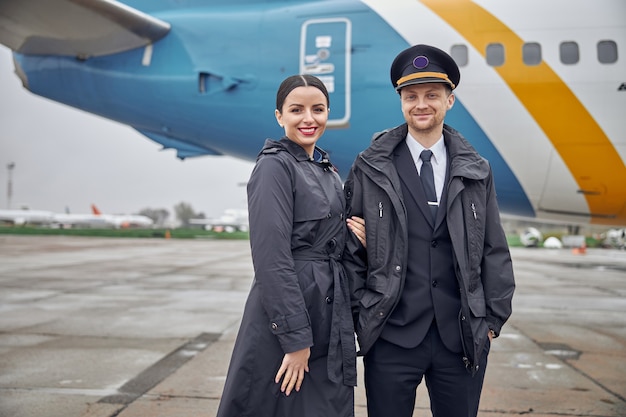 Porträt einer glücklichen, selbstbewussten kaukasischen Flugzeugbesatzung in der Nähe des Flugzeugs