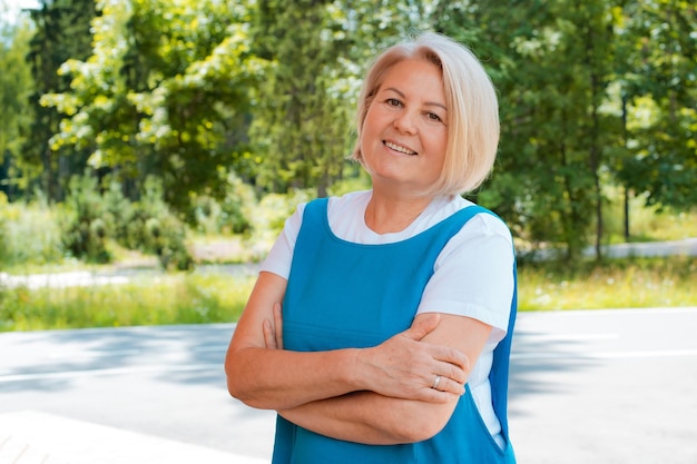 Porträt einer glücklichen Seniorin, die sich im Freien entspannt und frische Luft mit Sonnenlicht atmet Ältere Frau, die im Sommer einen Tag im Park genießt