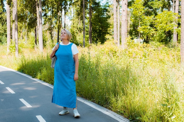 Porträt einer glücklichen Seniorin, die sich im Freien entspannt und frische Luft mit Sonnenlicht atmet Ältere Frau, die im Sommer einen Tag im Park genießt