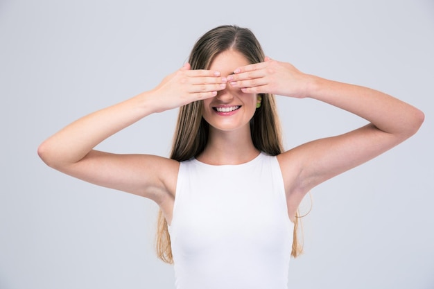 Porträt einer glücklichen Teenagerin, die ihre Augen isoliert bedeckt