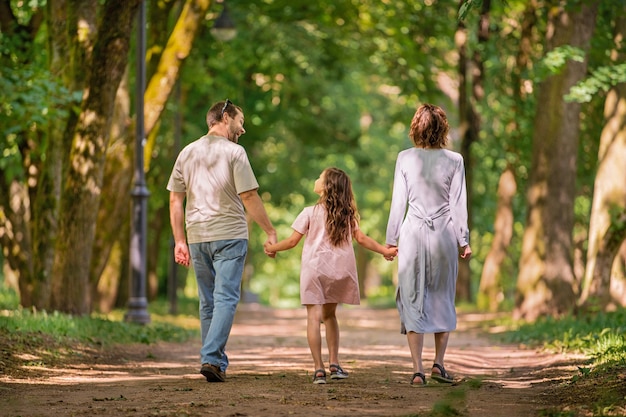 Porträt einer glücklichen traditionellen Familie bei einem Spaziergang in einem Sommerpark, Blick von hinten ohne Gesicht