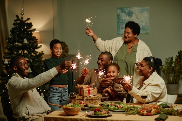 Porträt einer großen afroamerikanischen Familie, die Wunderkerzen anzündet, während sie gemeinsam Weihnachten zu Hause genießen