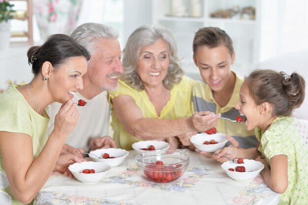 Porträt einer großen glücklichen Familie, die frische Erdbeeren in der Küche isst