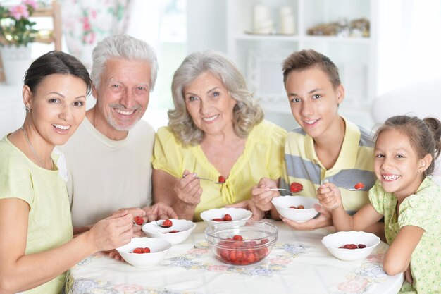 Porträt einer großen glücklichen Familie, die frische Erdbeeren isst