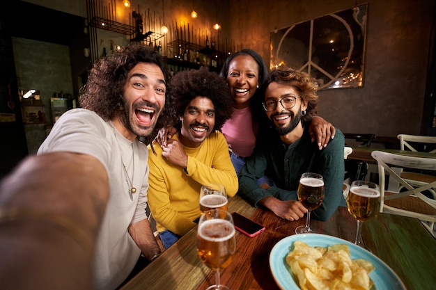 Porträt einer Gruppe multiracialer Freunde, die nach der Arbeit in einer Pub-Happy-Hour in einer Restaurantbar auf die Kamera schauen