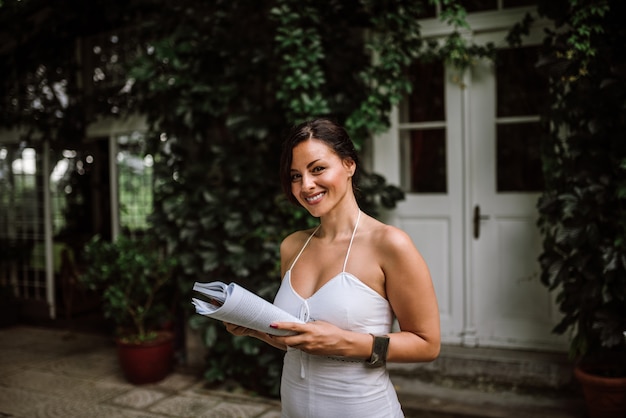 Porträt einer herrlichen Frau mit einem Buch im Hausgarten.