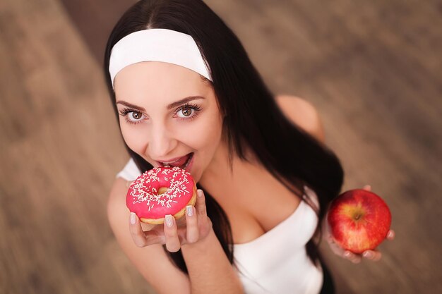 Porträt einer herrlichen jungen Brunettefrau, die Diätnahrungsmittelwahlen zeigt.