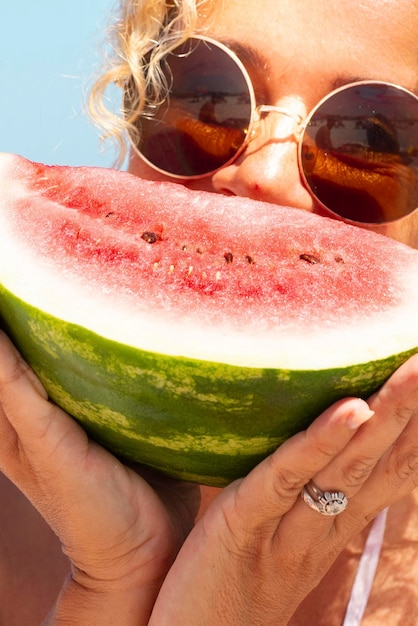 Porträt einer hübschen Frau und roter frischer Wassermelone mit blauem Meer und Himmel im Hintergrund. Konzept eines Sommerurlaubs. Gesunde Menschen und Vitaminernährung. Frauen genießen tropische Sonne