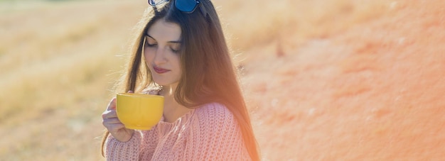 Porträt einer hübschen jungen Frau im stilvollen Strickpullover, die an einem sonnigen Tag auf dem goldenen Herbstwald steht