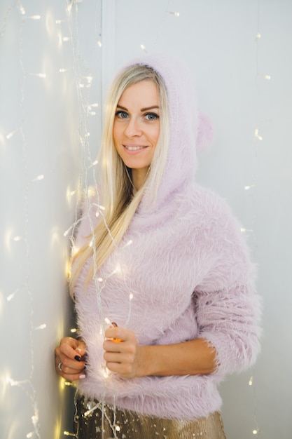 Porträt einer hübschen jungen Frau mit blondem Haar in einer Kapuze mit einer Weihnachtsstimmung