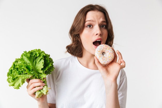 Porträt einer hungrigen jungen Frau, die Donut hält