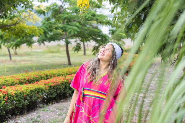 Porträt einer indigenen Frau in einem Naturpark, die die Natur an einem schönen Sommermorgen genießt, umgeben von Pflanzen